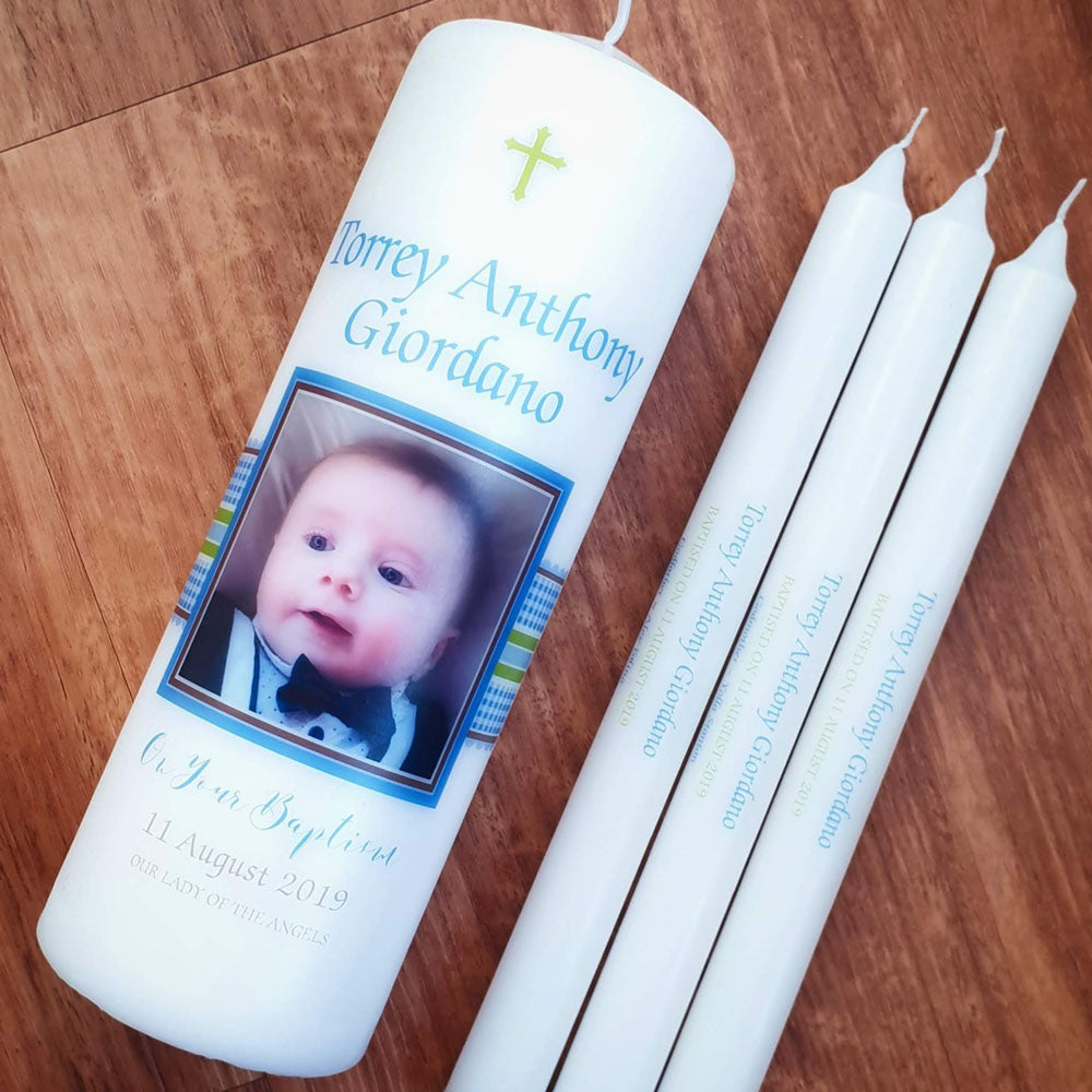 White pillar Baptism candle with a photo of a baby and blue checked ribbon with three personalised taper candles