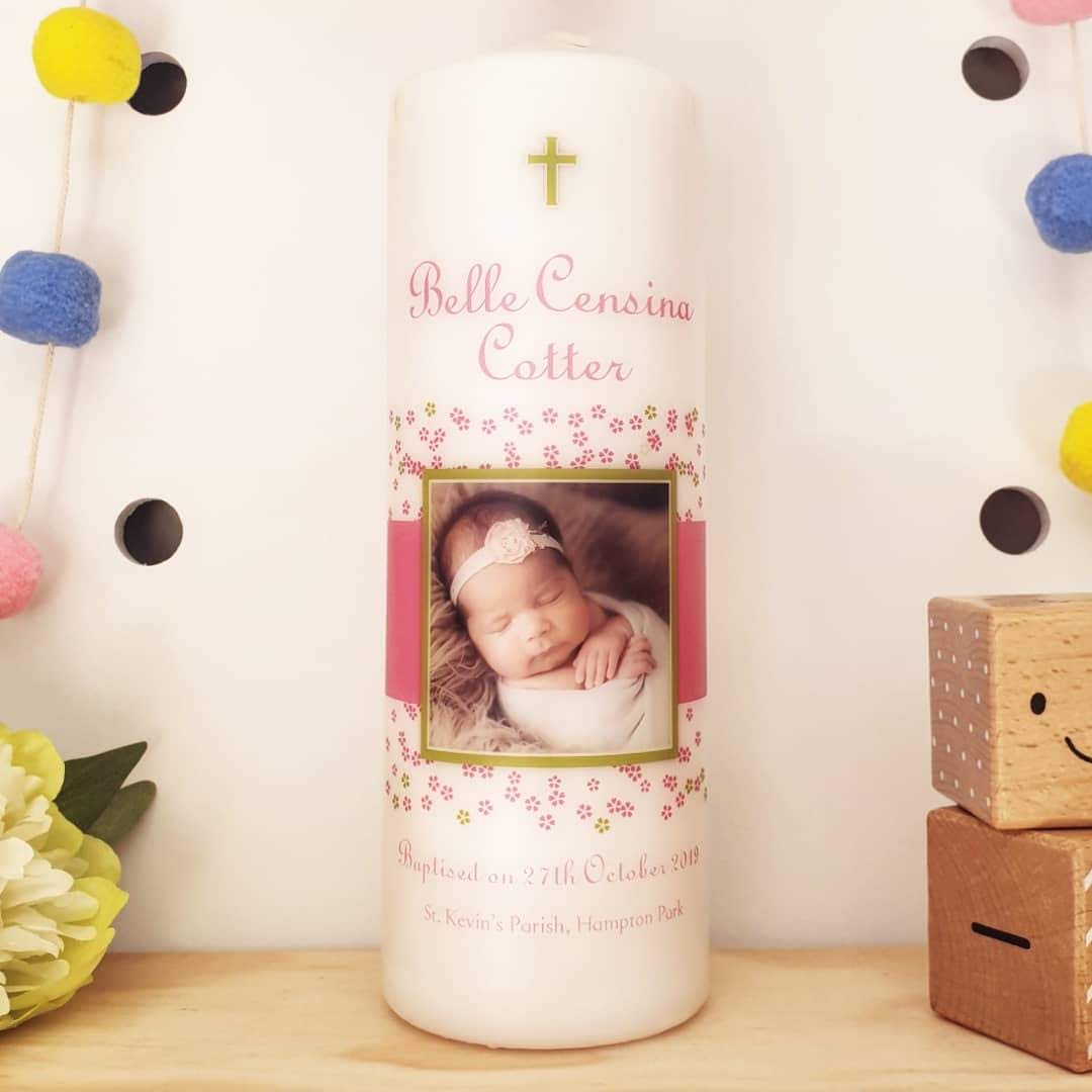 Baptism candle with a photo of a baby and flowers on it.