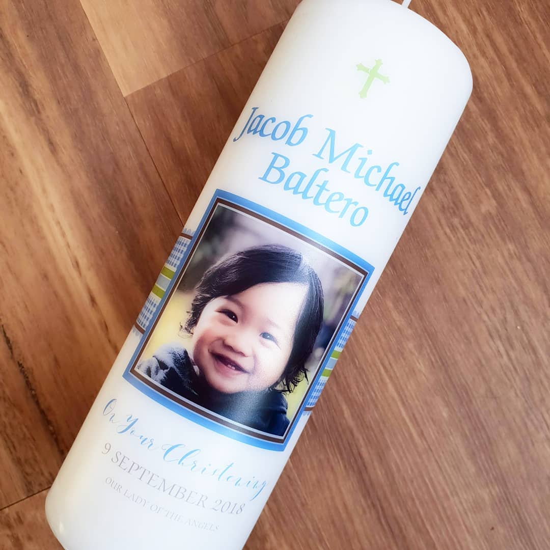 White pillar Baptism candle with a photo of a baby and blue checked ribbon